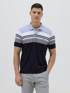 A man wearing a short-sleeve polo shirt with horizontal stripes in light blue, white, and navy, paired with light gray trousers, against a plain light gray background.