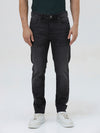 A person wearing slim-fit black denim jeans with a dark green top and white sneakers, shown from the waist down against a plain light gray studio background.