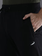 Black pants with a small logo on the side, worn by a person.