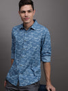 Man wearing a blue blue printed full sleeve shirt on a light gray background