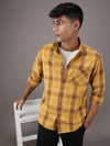 Man wearing a yellow yellow checked casual full sleeve 100% cotton shirt on a light gray background