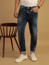 Man wearing a blue mid blue solid mid rise casual slim tapered jean on a light gray background