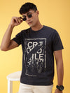 Man wearing a navy casual printed navy t shirt on a light gray background