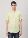 Man wearing a green light green solid half sleeve shirt on a light gray background
