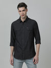 Man wearing a black black solid full sleeve 100% cotton casual shirt with casual styling on a gray background