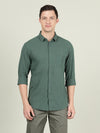 Man wearing a green green solid full sleeve linen casual shirt with casual styling on a gray background