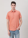 Man wearing a peach solid half sleeve linen shirt with casual styling on a gray background