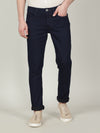 Man wearing a blue dark blue solid mid rise slim tapered jean on a light gray background